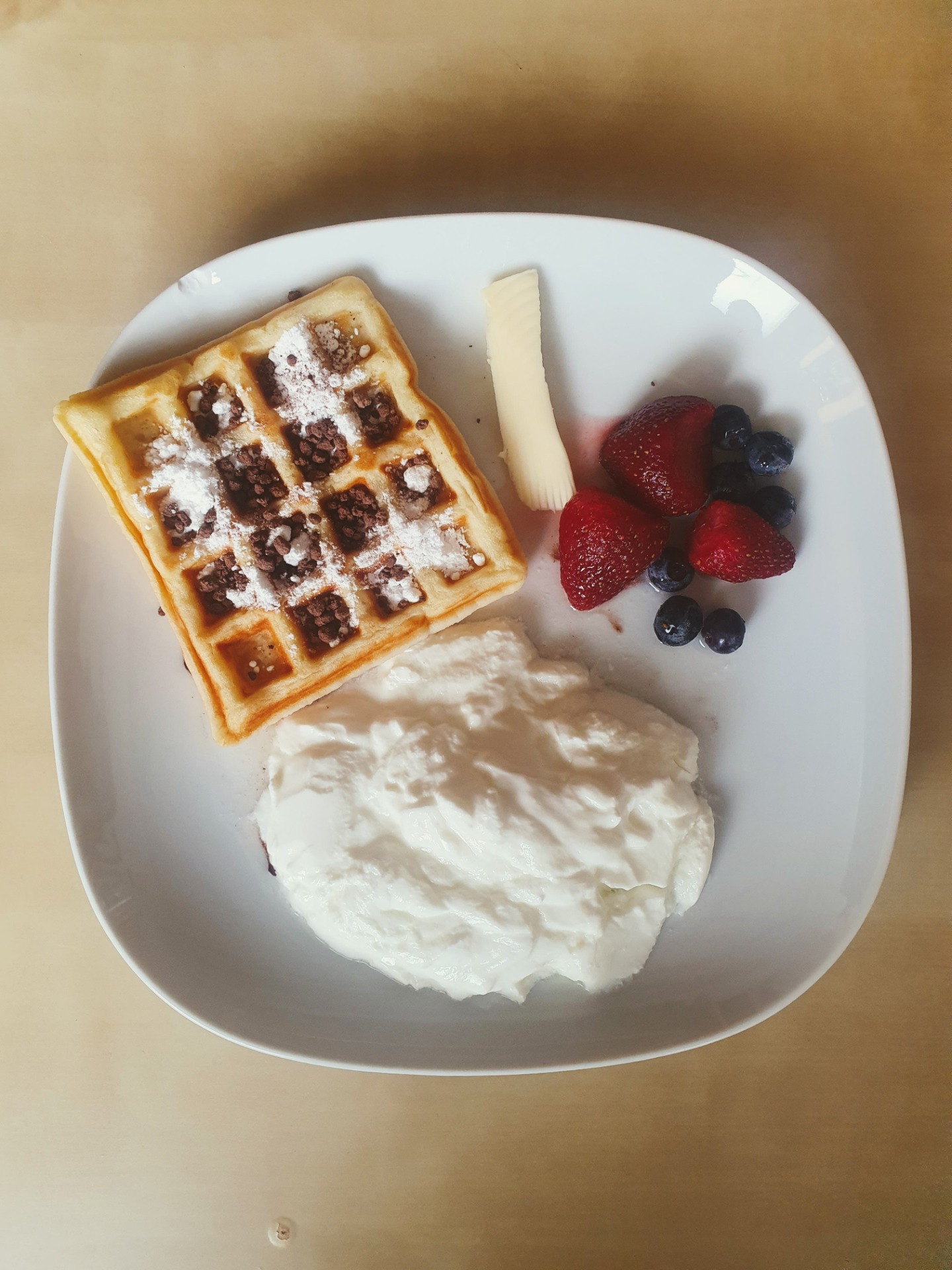 Domácí vafle s bílým jogurtem, ovocem, máslem, moučkovým cukrem a kakaem