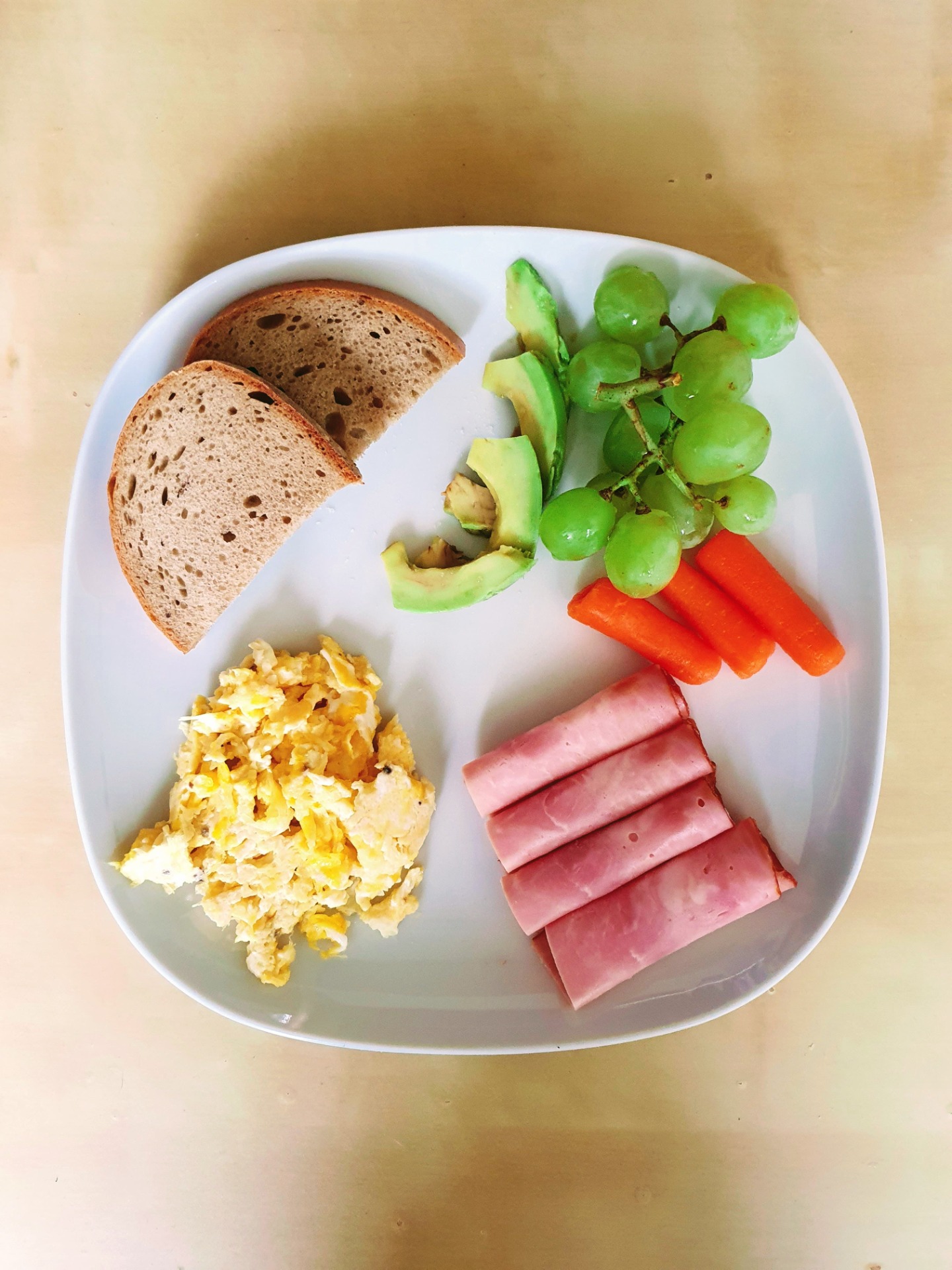 Sedlácký chléb s míchanými vajíčky, šunkou, mrkví, hroznovým vínem a avokádem