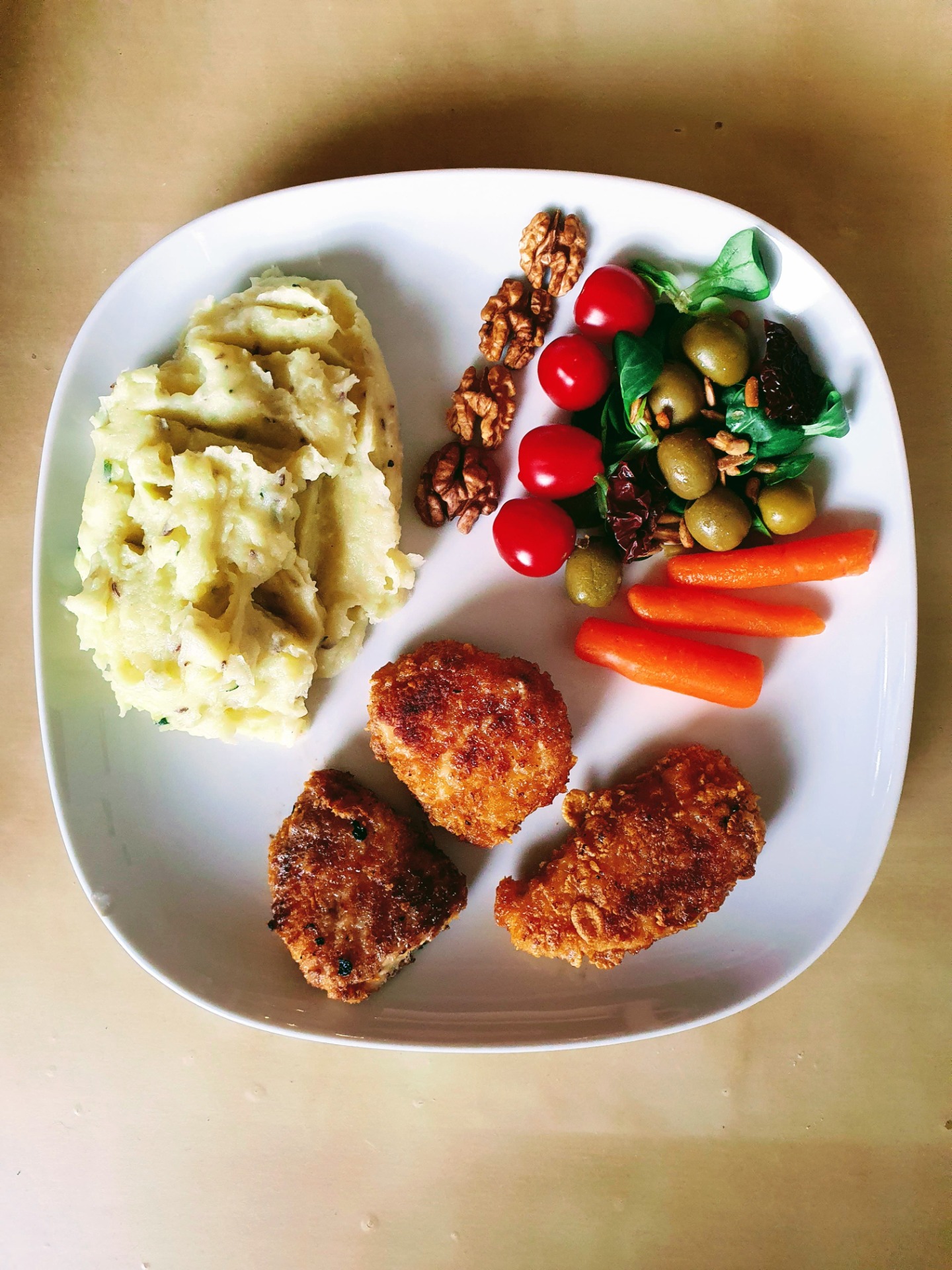 Kuřecí řízky v cornflakes s bramborovou kaší, polníčkem, mrkví, cherry rajčaty, sušenými rajčaty, olivami, slunečnicovými semínky a vlašskými ořechy